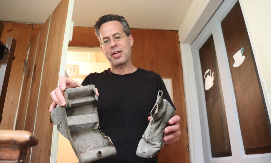 A homeowner of an 1812 house on Gaskill Street shows the students some of the belongings of immigrants a century ago, a shoe and toy sled unearthed in their attic.