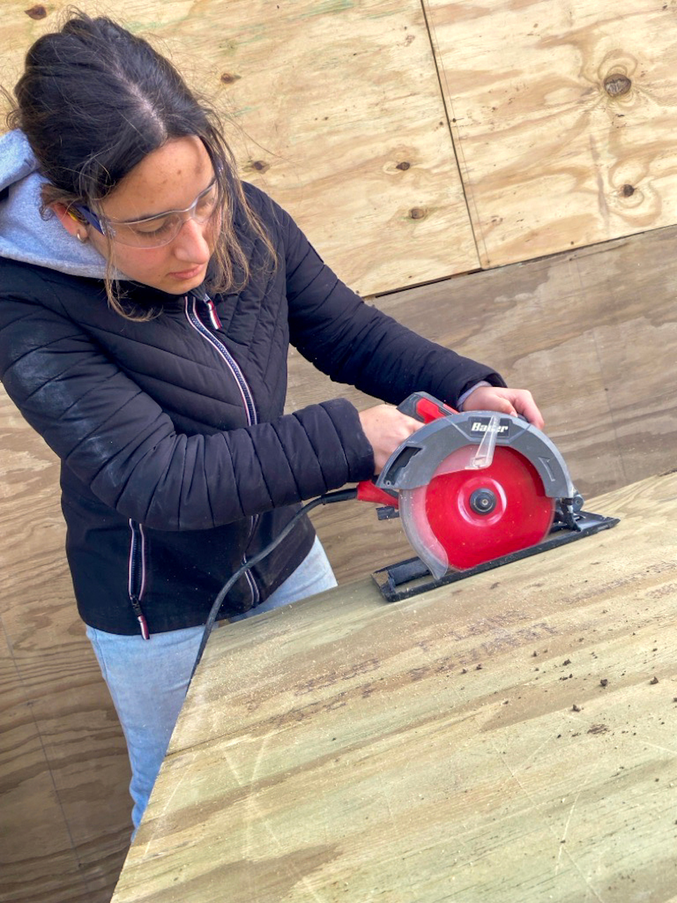 Juliette Jerome '26 cuts the plywood underlayment to size. 