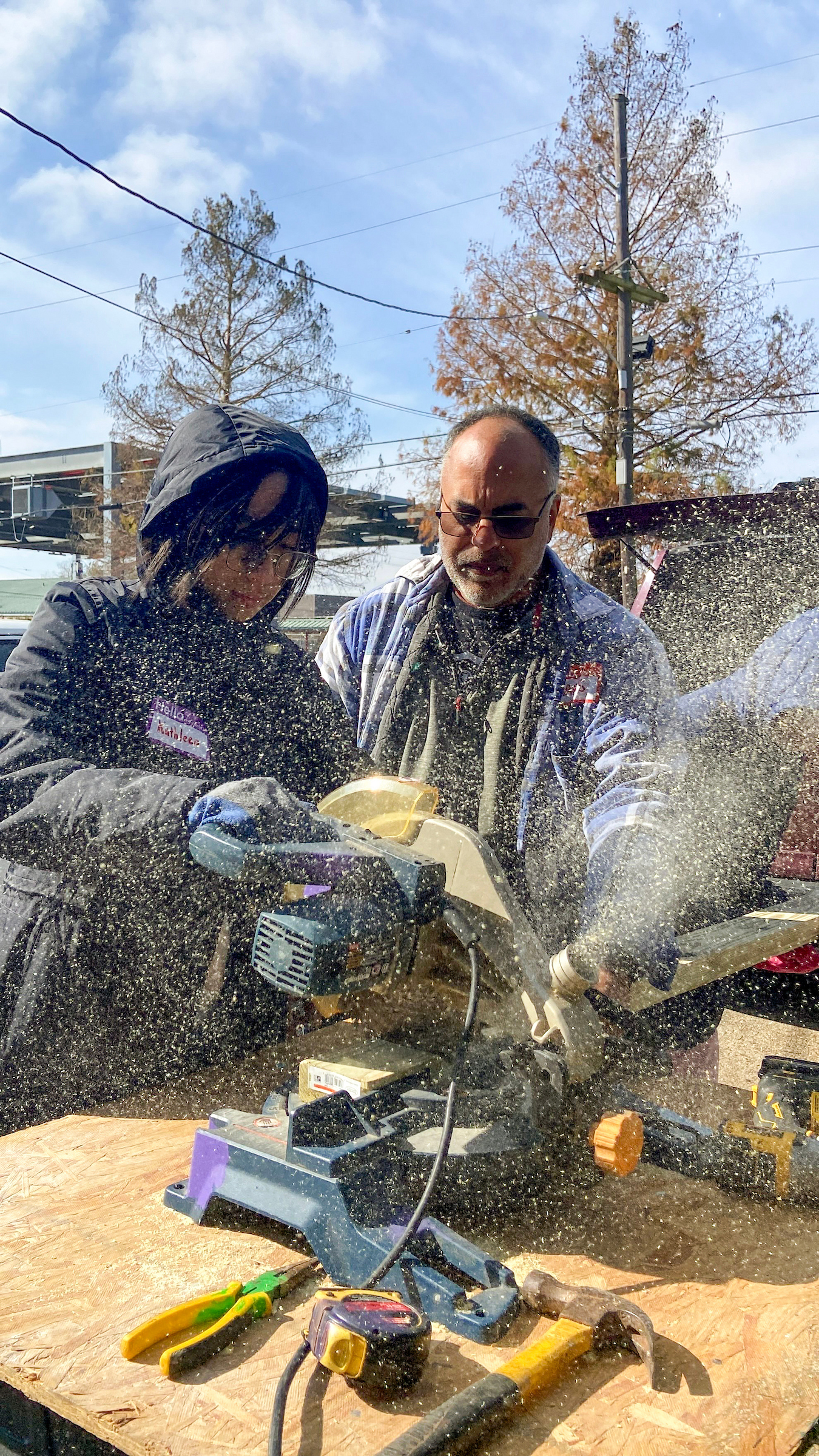 Kathleen Nguyen '26 chop-saws a stud for framing under the watchful supervision of Hans Gulati, CRA volunteer.