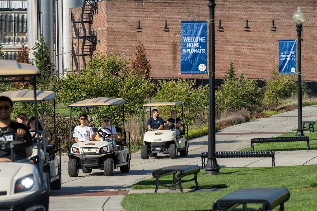 True Blue student volunteers drive golf carts at Shadek Stadium