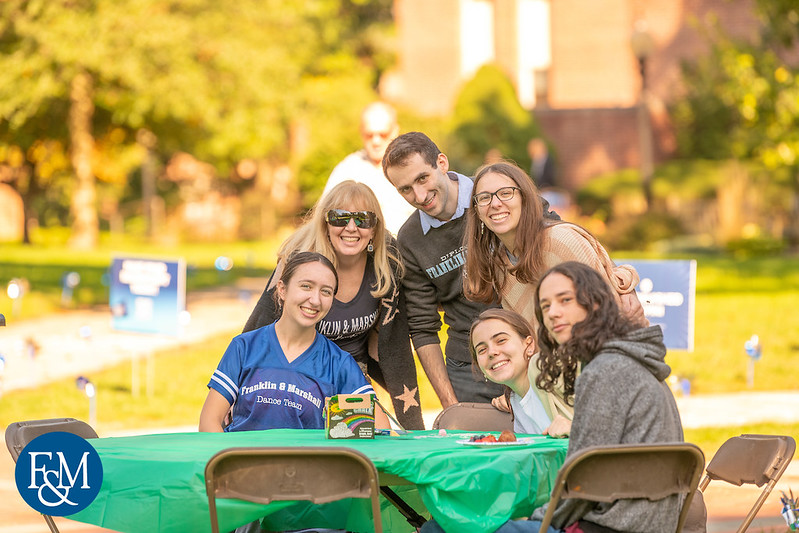 A family poses outside with smiles during True Blue Weekend