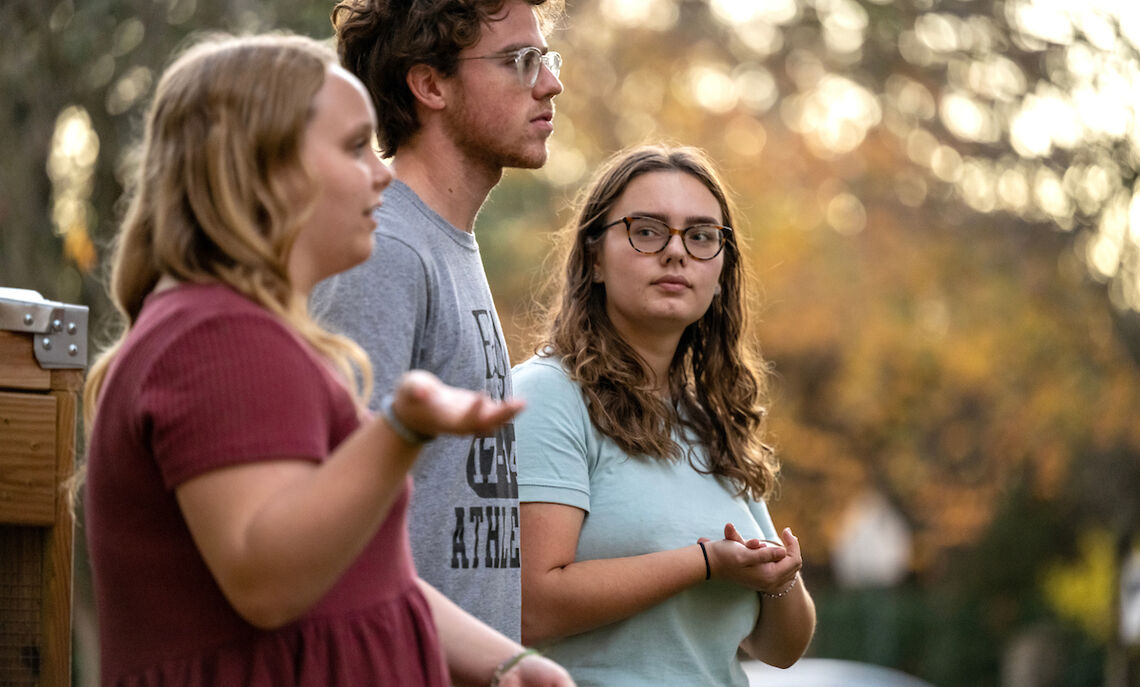 Caroline Kleis '24, Bennett Wasch '23, and Athena Kotsopriftis '25 discuss their involvement with Lancaster Composting Co-Ops. The Buchanan Park compost bin can be seen in the background.