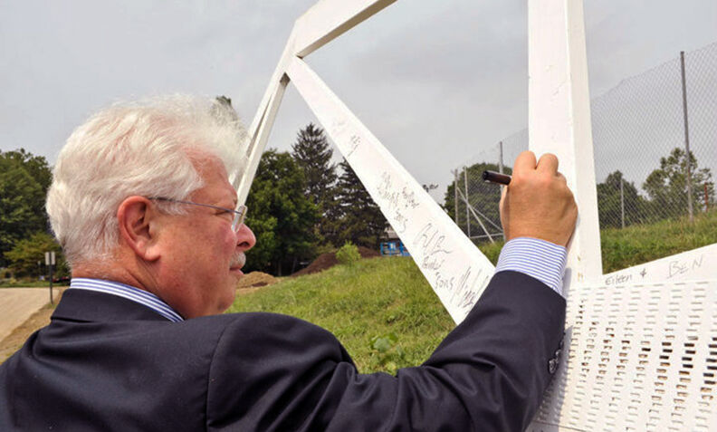 Former Interim President John F. Burness 67 signs a beam during a ceremony marking the construction of New College House (now Roschel College House) in 2010.