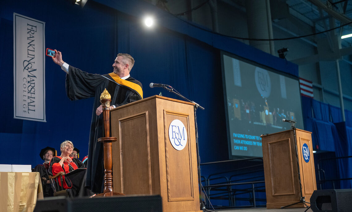 Commencement speaker Jacob Bleacher '00 takes a selfie with Class of 2023 graduates.