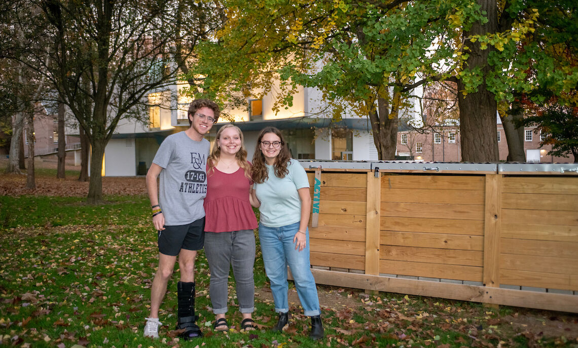 Caroline Kleis '24, Bennett Wasch '23, and Athena Kotsopriftis '25 discuss their involvement with Lancaster Composting Co-Ops. The Buchanan Park compost bin can be seen in the background.