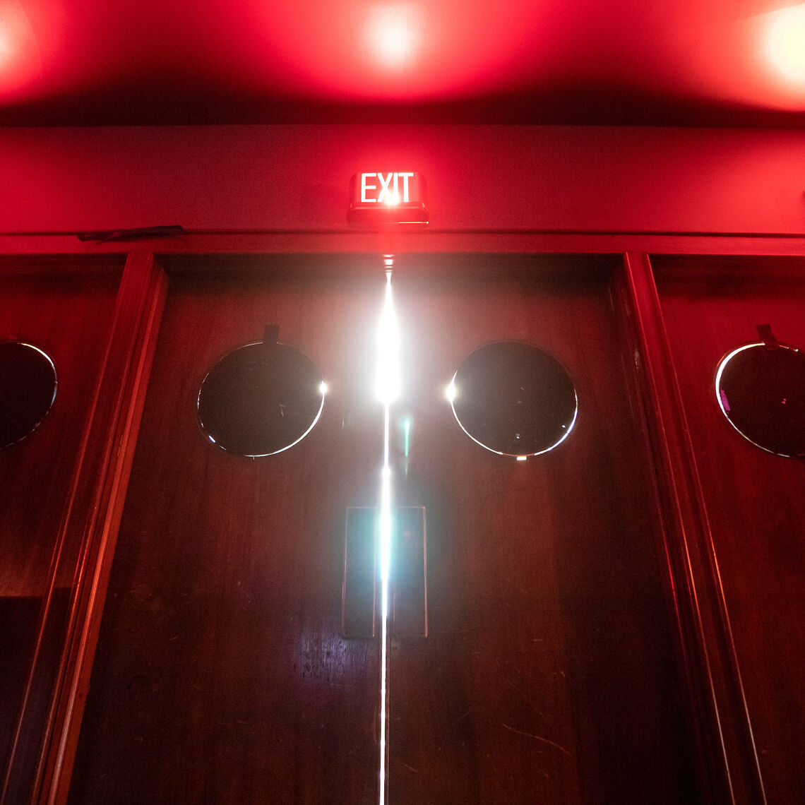 Faint red light from exit signs illuminates the entrance to the Green Room Theatre.