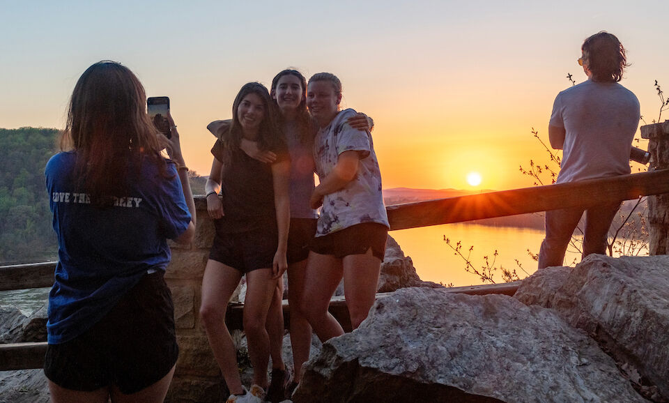 Students gather for photos with friends while the sun sets.